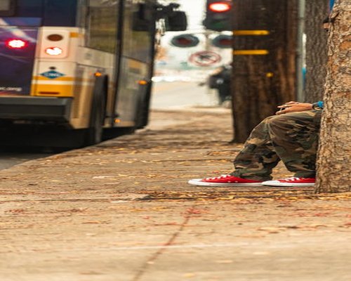 A person wearing comfortable sneakers waiting at a bus stop